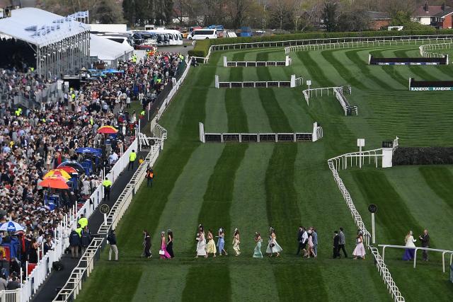 Racegoers cross the racecourse ahead of racing on day two of the Grand National Festival horse race meeting at Aintree Racecourse in Liverpool, north-west England, on April 10, 2026. (Photo by PETER POWELL / AFP)