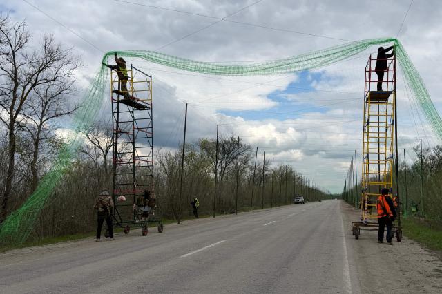 Ukrainian servicemen cover the road with a net to protect vehicles from drone attacks at an undisclosed location in the Zaporizhzhia region on April 10, 2026, amid the Russian invasion of Ukraine. (Photo by Darya NAZAROVA / AFP)