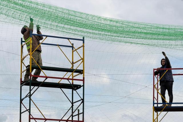 Ukrainian servicemen cover the road with a net to protect vehicles from drone attacks at an undisclosed location in the Zaporizhzhia region on April 10, 2026, amid the Russian invasion of Ukraine. (Photo by Darya NAZAROVA / AFP)