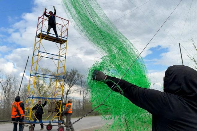 Ukrainian servicemen cover the road with a net to protect vehicles from drone attacks at an undisclosed location in the Zaporizhzhia region on April 10, 2026, amid the Russian invasion of Ukraine. (Photo by Darya NAZAROVA / AFP)