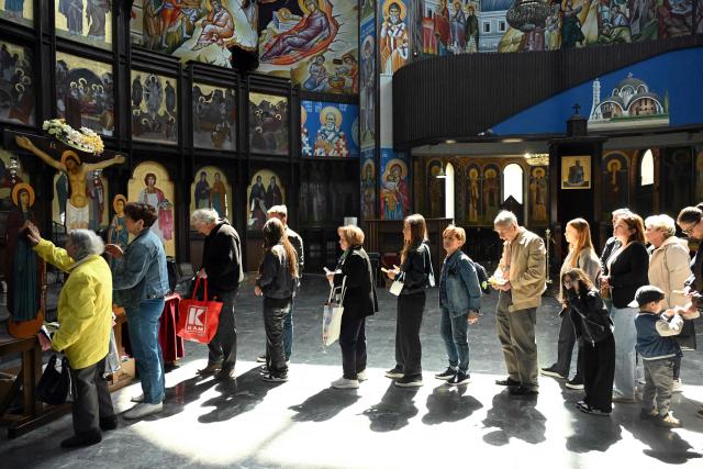 Faithfuls queue to touch a wooden statue of Jesus Christ on the cross during a Good Friday procession ahead of Orthodox Easter in Skopje on April 10, 2026. The North Macedonian Orthodox Church celebrates Easter according to the Julian calendar. (Photo by Robert ATANASOVSKI / AFP)