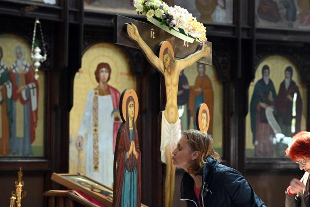 TOPSHOT - A faithful kisses kisses wooden statue of Jesus Christ on the cross during a Good Friday procession ahead of Orthodox Easter in Skopje on April 10, 2026. The North Macedonian Orthodox Church celebrates Easter according to the Julian calendar. (Photo by Robert ATANASOVSKI / AFP)