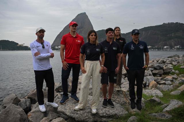 (L to R) US Taylor Canfield, Spain’s Diego Botin, Brazil’s Martine Grael, Brazil’s Marco Grael, Denmark’s Kahena Kunze, and France’s Quentin Delapierre pose for a picture at the Guanabara bay, with the Sugar Loaf mountain in the background, at the location of the Rio 2026 SailGP race in Rio de Janeiro, on April 10, 2026. (Photo by MAURO PIMENTEL / AFP)