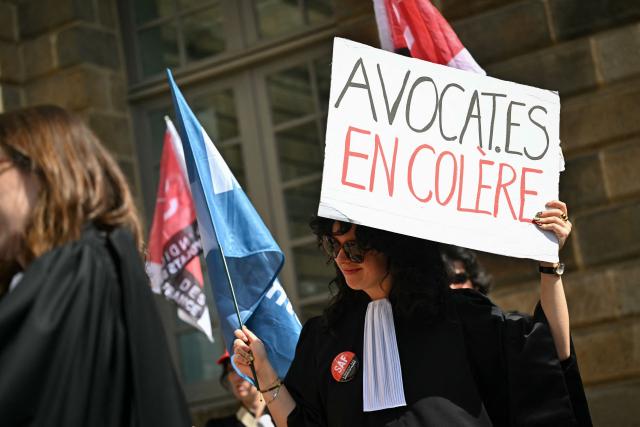 A lawyer holds a placard reading "Lawyers in anger" during a gathering in front of the Parlement of Brittany building as part of a national strike against a bill on criminal justice and respect for victims, in Rennes, western France, on April 10, 2026. (Photo by Lou BENOIST / AFP)