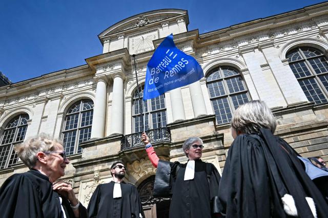 A lawyer holds a glad of the "Rennes Bar association" during a gathering in front of the Parlement of Brittany building as part of a national strike against a bill on criminal justice and respect for victims, in Rennes, western France, on April 10, 2026. (Photo by Lou BENOIST / AFP)