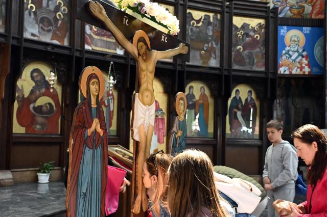 A faithful kisses kisses wooden statue of Jesus Christ on the cross during a Good Friday procession ahead of Orthodox Easter in Skopje on April 10, 2026. The North Macedonian Orthodox Church celebrates Easter according to the Julian calendar. (Photo by Robert ATANASOVSKI / AFP)