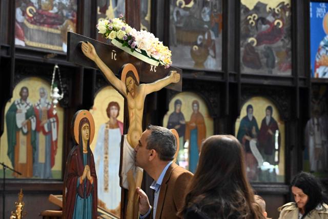 A faithful kisses kisses wooden statue of Jesus Christ on the cross during a Good Friday procession ahead of Orthodox Easter in Skopje on April 10, 2026. The North Macedonian Orthodox Church celebrates Easter according to the Julian calendar. (Photo by Robert ATANASOVSKI / AFP)