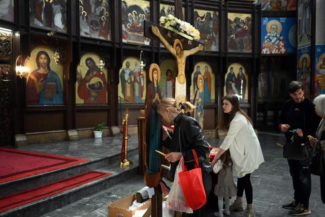 Believers touch a wooden statue of Jesus  Christ during a Good Friday service at the main Orthodox church St. Kliment of Ohrid in Skopje on April 10, 2026. The North Macedonian Orthodox Church celebrates Easter according to the Julian calendar. (Photo by Robert ATANASOVSKI / AFP)