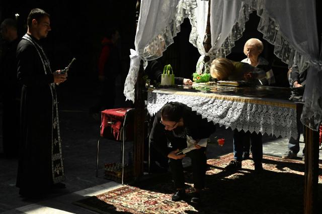 A woman passes under a table symbolising the grave of Jesus Christ during a Good Friday service at the main Orthodox church St. Kliment of Ohrid in Skopje on April 10, 2026. The North Macedonian Orthodox Church celebrates Easter according to the Julian calendar. (Photo by Robert ATANASOVSKI / AFP)