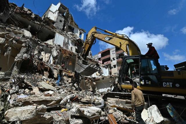 This photograph taken on April 10, 2026, during a media tour organized by Hezbollah’s media office shows a digger clearing the rubble of a building in Beirut's Hay al-Selloum neighbourhood, that was targetted in an Israeli strike earlier this week. The Israeli military said on April 10 that it had "dismantled" more than 4,300 Hezbollah sites in Lebanon since fighting with the militant group began last month. (Photo by FADEL itani / AFP) / 