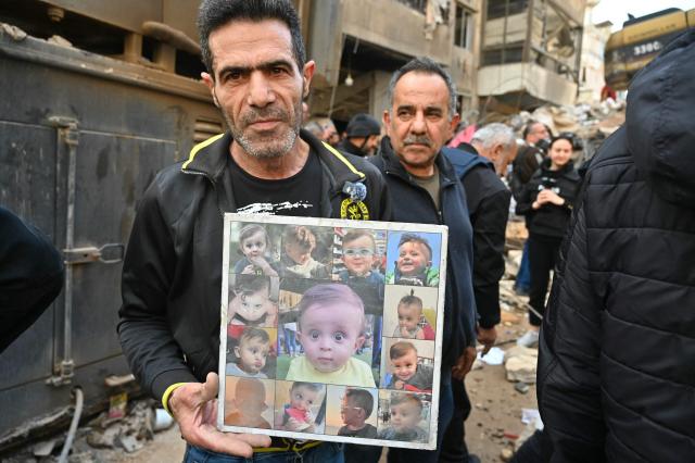 This photograph taken on April 10, 2026, during a media tour organized by Hezbollah’s media office shows a man holding photos of children that were allegedly killed during Israeli strikes in Beirut's Hay al-Selloum neighbourhood. The Israeli military said on April 10 that it had "dismantled" more than 4,300 Hezbollah sites in Lebanon since fighting with the militant group began last month. (Photo by FADEL itani / AFP) / 