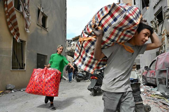 This photograph taken on April 10, 2026, during a media tour organized by Hezbollah’s media office shows residents carrying salvaged belognings at southern Beirut's Chweifat-Amrousiyeh neighbourhood that was targetted in an Israeli strike earlier this week. The Israeli military said on April 10 that it had "dismantled" more than 4,300 Hezbollah sites in Lebanon since fighting with the militant group began last month. (Photo by FADEL itani / AFP) / 