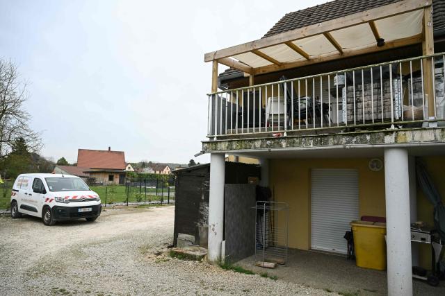 A photo shows a residential building, with the involved suspects' terrace at the first level (R), and parking area at the location where a boy was discovered naked and malnourished on a pile of rubbish in a van where he had been kept locked up, in Hagenbach, eastern France, on April 10, 2026. Gendarmes discovered the child on April 6, 2026, after being alerted by a local resident who had heard “the sounds of a child” coming from a van parked in a resident's courtyard. The nine-year-old endured a nightmare for over a year in the small village of southern Alsace, according to the public prosecutor in Mulhouse, who announced on April 10 that the boy’s father and his partner had been charged. (Photo by SEBASTIEN BOZON / AFP)