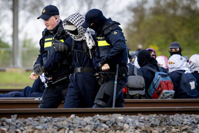 Mobile Unit police officers take activists from Geef Tegengas away as they block a railway line while protesting against human rights violations worldwide and the climate crisis near Elst on April 10, 2026. (Photo by Sem van der Wal / ANP / AFP) / Netherlands OUT