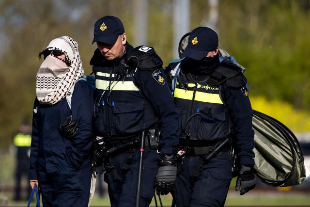 Mobile Unit police officers take activists from Geef Tegengas away as they block a railway line while protesting against human rights violations worldwide and the climate crisis near Elst on April 10, 2026. (Photo by Sem van der Wal / ANP / AFP) / Netherlands OUT