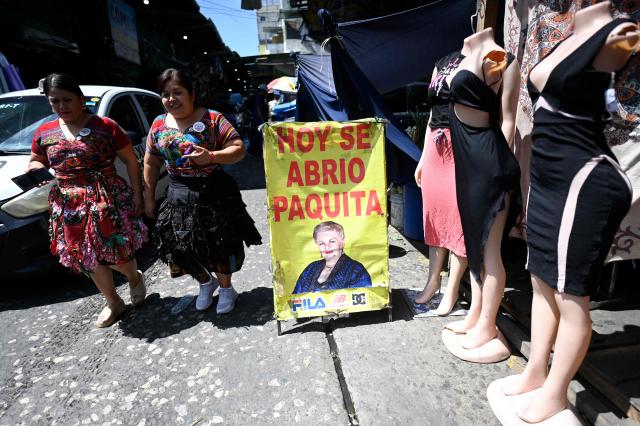 Women walk past a stall selling second-hand clothes at La Terminal market in Guatemala City on April 10, 2026. (Photo by JOHAN ORDONEZ / AFP)