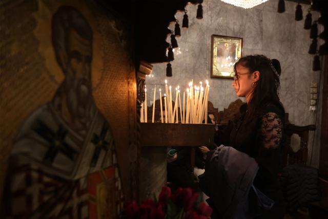 A woman lights a candle ahead of Good Friday mass at the Greek Orthodox church of Saing Porphyrius in Gaza City on April 10, 2026. (Photo by Omar AL-QATTAA / AFP)