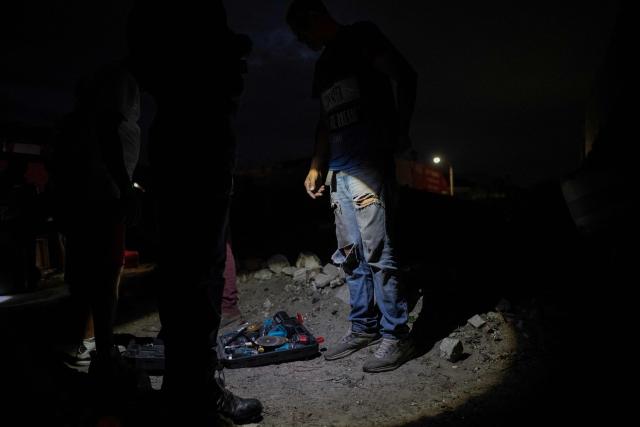 A man stands next to a case of tools he has opened as South African Police Service (SAPS) officers, supported by unseen soldiers of the South African National Defence Force (SANDF), search people living in a shack as part of Operation Prosper in Retreat, near Cape Town, on April 10, 2026. Operation Prosper sees the SANDF play a supporting role to the South African Police Service(SAPS) in crime prevention operations. (Photo by RODGER BOSCH / AFP)