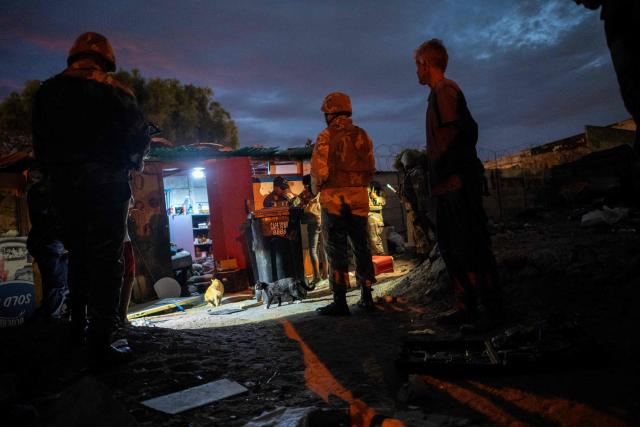 Officers of the South African Police Service (SAPS) supported by soldiers of the South African National Defence Force (SANDF) search people living in a shack as part of Operation Prosper in Retreat, near Cape Town, on April 10, 2026. Operation Prosper sees the SANDF play a supporting role to the South African Police Service(SAPS) in crime prevention operations. (Photo by RODGER BOSCH / AFP)