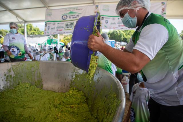 A participant prepares a portion of 6,800 kilos of Guacamole, a traditional Mexican dish made from avocados, tomatoes, onions, limes and coriander in Tancitaro, Michoacan state, Mexico on April 10, 2026. 800 people used 12 tons of avocados to complete the task on an attempt to break the Guinness World Record for the largest guacamole. Tancitaro is recognized as the "Avocado Capital," and the leading exporter of avocados to the US. (Photo by Enrique Castro / AFP)