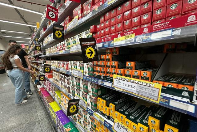 People check the prices of coffee capsules on sale at a supermarket in Buenos Aires on April 10, 2026. (Photo by AFP)