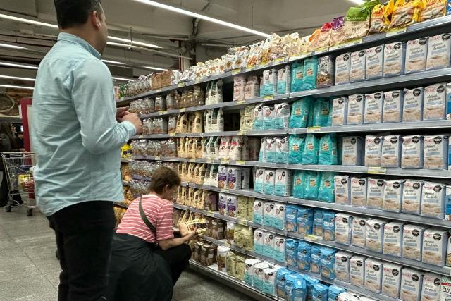 People check the prices of flour at a supermarket in Buenos Aires on April 10, 2026. (Photo by AFP)