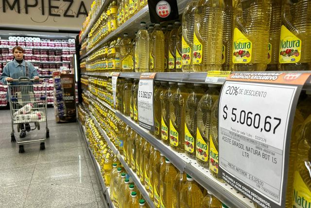 A woman pushes a shopping cart past sunflower oil on sale at a supermarket in Buenos Aires, on April 10, 2026. (Photo by AFP)