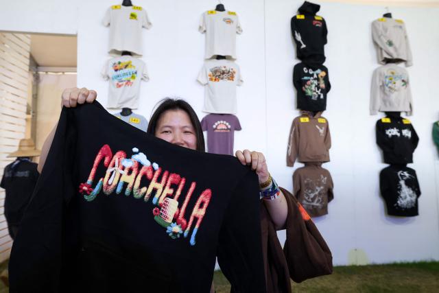 A festival-goer holds up Coachella merchandise during the 2026 Coachella Valley Music and Arts Festival at Empire Polo Club in Indio, California on April 10, 2026. (Photo by VALERIE MACON / AFP)