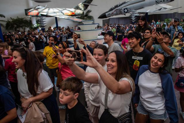 People celebrate as they watch a live broadcast of the return of the Artemis II crew members to Earth at the San Diego Air and Space Museum during a watch party for the crew's splash down in the Pacific Ocean, in San Diego, California, on April 10, 2026. The NASA spacecraft carrying four astronauts splashed down as planned Friday off the California coast, capping the US space agency's successful crewed test mission around the Moon, the first such flyby in more than 50 years. Mission commander Reid Wiseman reported that the crewmembers -- himself along with Christina Koch, Victor Glover and Jeremy Hansen -- were "stable" and "green." (Photo by Apu GOMES / AFP)