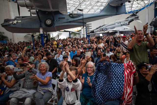 People celebrate as they watch a live broadcast of the return of the Artemis II crew members to Earth at the San Diego Air and Space Museum during a watch party for the crew's splash down in the Pacific Ocean, in San Diego, California, on April 10, 2026. The NASA spacecraft carrying four astronauts splashed down as planned Friday off the California coast, capping the US space agency's successful crewed test mission around the Moon, the first such flyby in more than 50 years. Mission commander Reid Wiseman reported that the crewmembers -- himself along with Christina Koch, Victor Glover and Jeremy Hansen -- were "stable" and "green." (Photo by Apu GOMES / AFP)