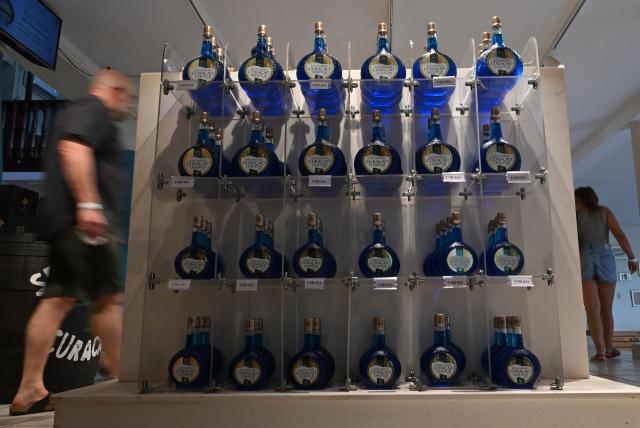 Curacao liquor bottles are seen at The Curacao Liqueur Distillery in Willemstad, Curacao, in the Dutch Caribbean, on April 9, 2026. The iconic blue color of Curaзao liquor is not natural; it is obtained by adding a coloring agent designed to evoke the turquoise waters of the island’s idyllic Caribbean beaches. (Photo by Raul ARBOLEDA / AFP)