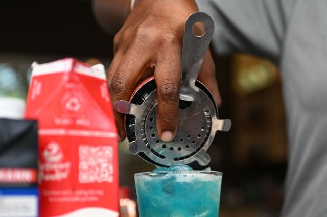 A bartender prepares a cocktail at The Curacao Liqueur Distillery in Willemstad, Curacao, in the Dutch Caribbean, on April 9, 2026. The iconic blue color of Curaзao liquor is not natural; it is obtained by adding a coloring agent designed to evoke the turquoise waters of the island’s idyllic Caribbean beaches. (Photo by Raul ARBOLEDA / AFP)