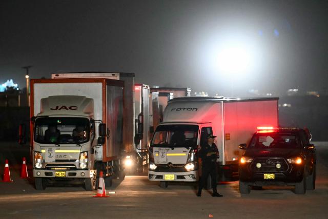 A police officer guards trucks loaded with voting materials at Peru's National Office of Electoral Processes (ONPE) facilities in Lima on April 10, 2026. (Photo by Luis ROBAYO / AFP)