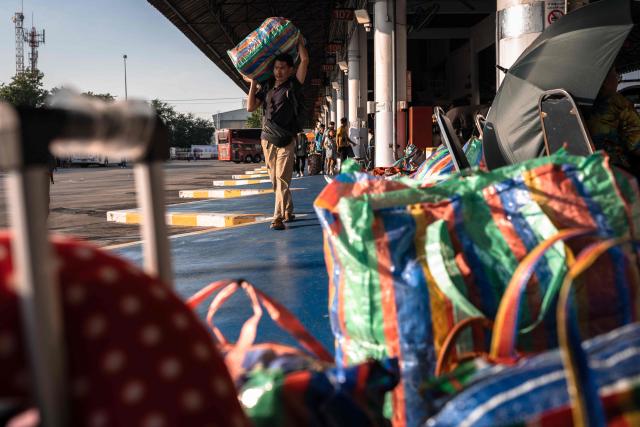 A man carries his belongings while waiting for a bus to return to his hometown at the Mo Chit 2 terminal in Bangkok on April 10, 2026, ahead of Thai New Year or Songkran celebrations. (Photo by chanakarn LAOSARAKHAM / AFP)