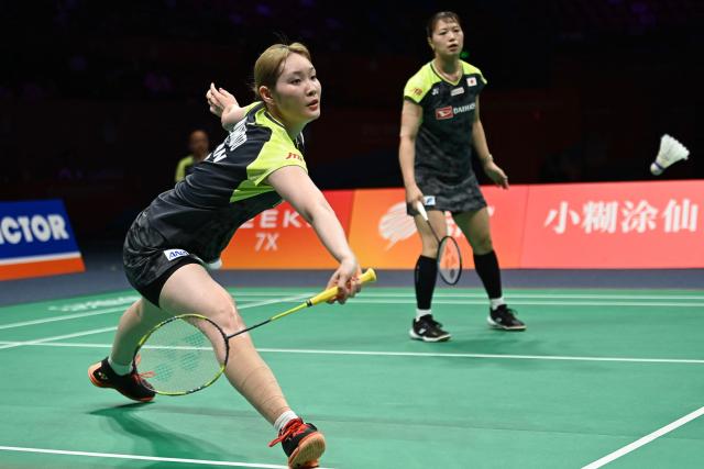 Mayu Matsumoto (L) and Yuki Fukushima of Japan hit a return to Li Yijing and Luo Xumin of China during their women's doubles semifinal match at the Badminton Asia Championship in Ningbo, eastern China's Zhejiang province on April 11, 2026. (Photo by CN-STR / AFP) / China OUT