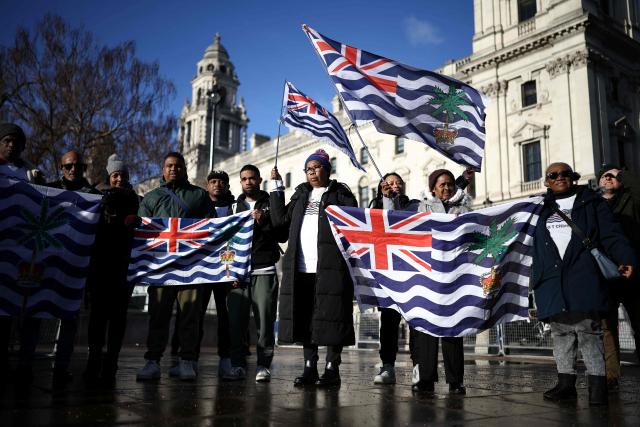 (FILES) Supporters and members of the British Indian Ocean territory Chagos Archipelago hold placards and the territory's flag outside the Houses of Parliament in London on January 7, 2026, to protest against a proposed plan by the British government to hand over the islands to Mauritius. Britain is shelving its plan to hand back the Chagos Islands -- which hosts the strategic Diego Garcia US-UK military base -- according to a government spokesperson on April 11, 2026, following strong opposition from US President Donald Trump. (Photo by Henry NICHOLLS / AFP)