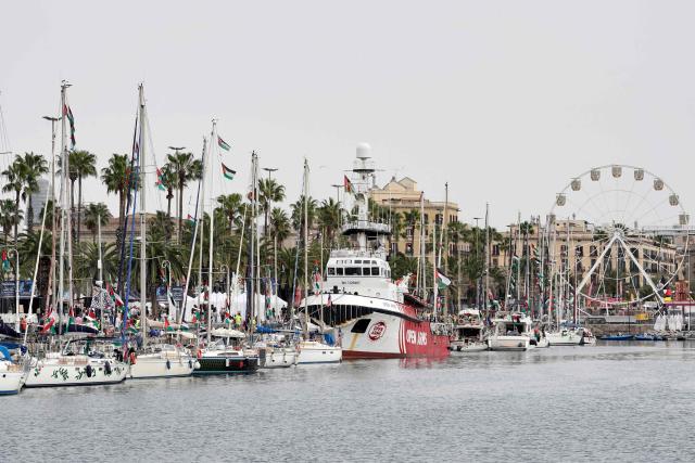 The NGO ship Open Arms (C) is moored next to other vessels of a new humanitarian flotilla bound for the Gaza Strip at the port of Barcelona on April 11, 2026, on the eve of their departure. A new flotilla of more than 80 boats and 1,000 international pro-Palestinian activists, who attempted to reach Gaza last year, is preparing for a new mission to the devastated territory from Barcelona tomorrow. Israel's response to the Global Sumud Flotilla's first journey —intercepting the boats and arresting the activists— sparked international condemnation. (Photo by Manaure Quintero / AFP)