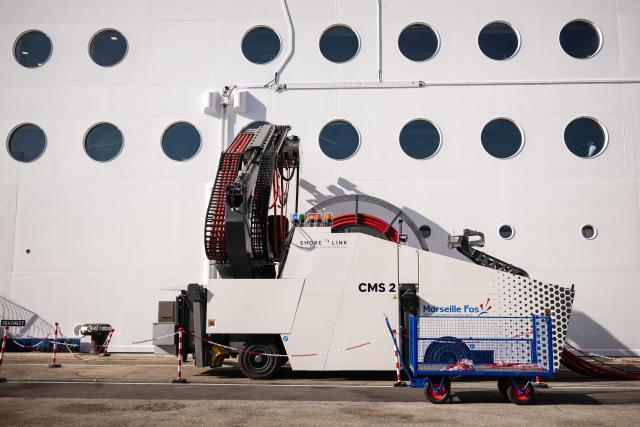 This photograph shows the MSC World Europa cruise boat moored at the Marseille cruise terminal while being charged using a "Cable Management System" at the Grand Port Maritime de Marseille, in Marseille, south-eastern France on April 11, 2026. Those systems allow boats to turn their engine off during their stay in Marseille harbour and to be charged by electricity. This new facilities are able to connect simultaneously three large cruise ships via electrical connection aiming to reduce smoke, vibrations and noise pollution in the city center. (Photo by CLEMENT MAHOUDEAU / AFP)