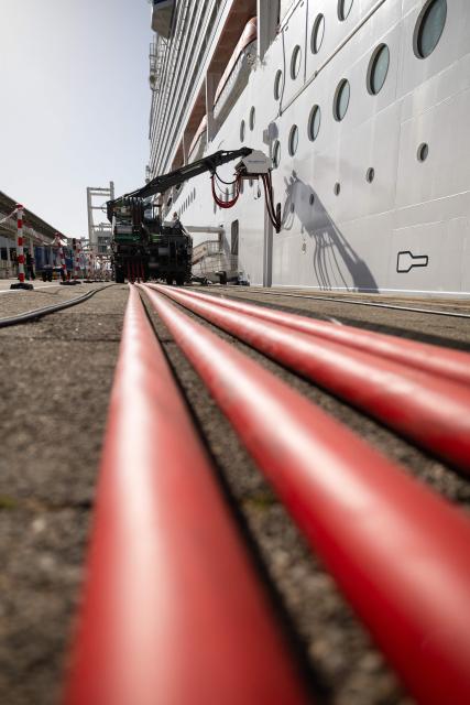 This photograph shows the MSC World Europa cruise boat moored at the Marseille cruise terminal while being charged using a "Cable Management System" at the Grand Port Maritime de Marseille, in Marseille, south-eastern France on April 11, 2026. Those systems allow boats to turn their engine off during their stay in Marseille harbour and to be charged by electricity. This new facilities are able to connect simultaneously three large cruise ships via electrical connection aiming to reduce smoke, vibrations and noise pollution in the city center. (Photo by CLEMENT MAHOUDEAU / AFP)