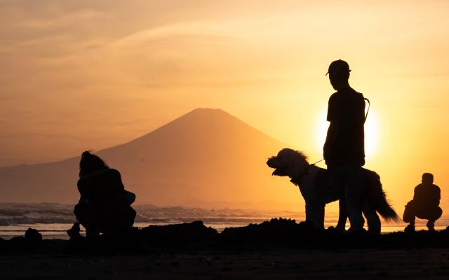 People stop to take sunset photos of Mt. Fuji at the Katase Nishihama beach in Fujisawa, Kanagawa Prefecture on April 11, 2026. (Photo by Andrew CABALLERO-REYNOLDS / AFP)
