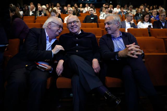 French writer and member of the French Academy Erik Orsenna (L) speaks with former French Prime Minister Bernard Cazeneuve (C) and Les Gracques' president Bernard Spitz during a debate session of the “Grand Dйbat des Gracques” on major national issues, at the Theatre de la Cite Internationale in Paris on April 11, 2026. (Photo by Ian LANGSDON / AFP)