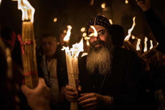 A Christian Orthodox priest holds a candle as he attends the annual Holy Fire ceremony at the Church of the Holy Sepulchre in Jerusalem's Old City on April 11, 2026. (Photo by MARCO LONGARI / AFP)