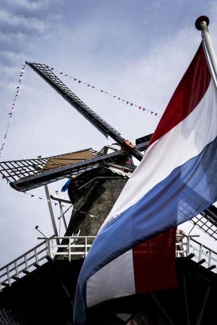 A photo shows a Dutch flag and the renovated grain and oil windmill De Wachter, which celebrates its 175th anniversary, during its opening following renovation, in Zuidlaren, on April 11, 2026. Princess Beatrix is the patron of De Hollandsche Molen, the association dedicated to the preservation of windmills in the Netherlands. (Photo by Siese VEENSTRA / ANP / AFP) / Netherlands OUT
