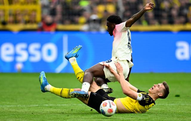 Bayer Leverkusen's Dutch forward #19 Ernest Poku (top) and Dortmund's German defender #04 Nico Schlotterbeck vie for the ball during the German first division Bundesliga football match between Borussia Dortmund and Bayer Leverkusen in Dortmund, western Germany, on April 11, 2026. (Photo by INA FASSBENDER / AFP) / DFL REGULATIONS PROHIBIT ANY USE OF PHOTOGRAPHS AS IMAGE SEQUENCES AND/OR QUASI-VIDEO