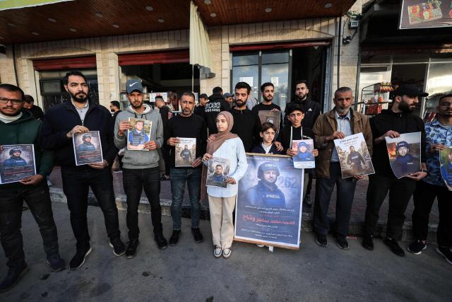 Fifteen-year-old Samia stands with Palestinians as they gather, holding images of her father, Mohammed Wishah, a journalist for the Qatar-based broadcaster Al-Jazeera Mubasher who was killed in an Israeli attack in the Bureij Refugee Camp on April 8, during a solidarity rally in Deir al Balah in the Gaza Strip on April 11, 2026. The Israeli military said on April 9, 2026, that an Al Jazeera journalist killed a day earlier in an Israeli strike in Gaza was a Hamas militant who had "operated under the guise of a journalist". (Photo by Eyad Baba / AFP)