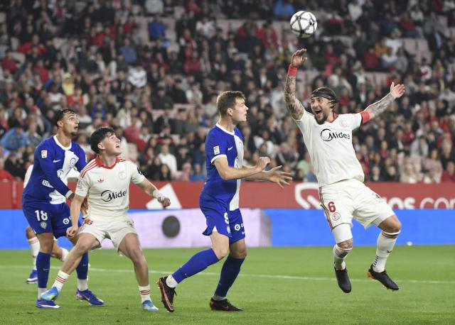 Sevilla's Serbian midfielder #06 Nemanja Gudelj (R) jumps for the ball during the Spanish league football match between Sevilla FC and Club Atletico de Madrid at the Ramon Sanchez Pizjuan stadium in Seville on April 11 , 2026. (Photo by CRISTINA QUICLER / AFP)