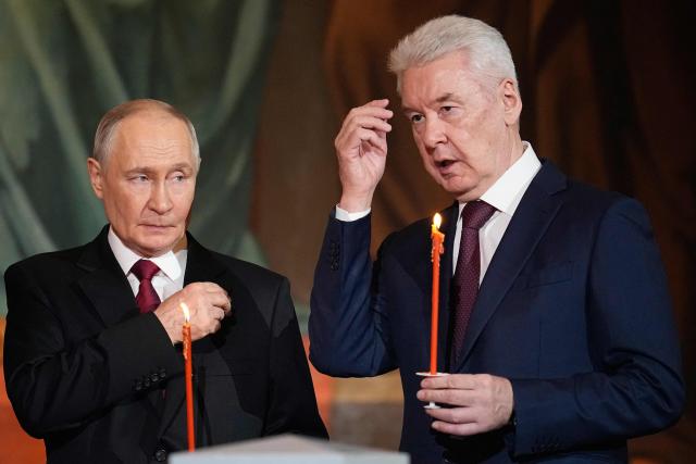 Russia's President Vladimir Putin (L) and Moscow Mayor Sergey Sobyanin (R) make the sign of the cross as they attend the Orthodox Easter service at the Cathedral of Christ the Saviour in Moscow on April 12, 2026. (Photo by Alexander Zemlianichenko / POOL / AFP)