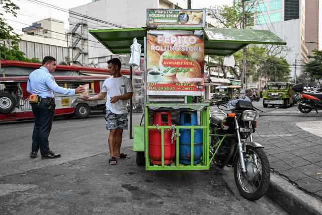 A man sells the popular breakfast roll 'pandesal' in Manila on April 7, 2026. While sticker shock at petrol stations has garnered the biggest headlines since the war in the Middle East forced the partial closure of the Strait of Hormuz, the rising price of LPG has hit the import-dependent archipelago's humble street food vendors hard. (Photo by Jam STA ROSA / AFP) / TO GO WITH AFP STORY: Iran-War-US-Israel-Philippines-economy-LPG, by Pam CASTRO