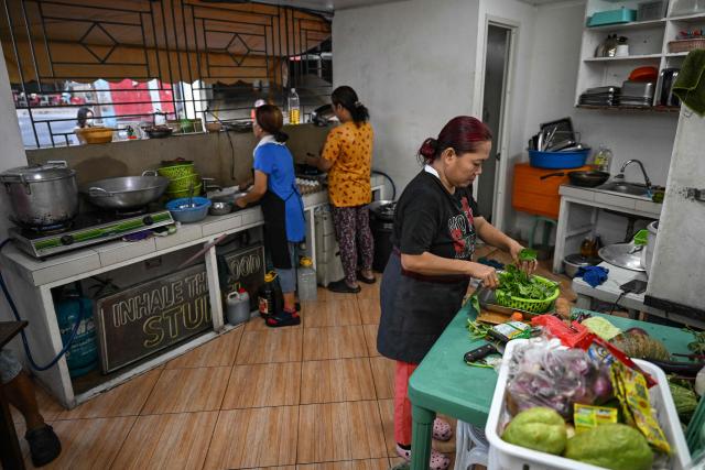 Women cook at a curbside canteen in Manila on April 7, 2026. While sticker shock at petrol stations has garnered the biggest headlines since the war in the Middle East forced the partial closure of the Strait of Hormuz, the rising price of LPG has hit the import-dependent archipelago's humble street food vendors hard. (Photo by Jam STA ROSA / AFP) / TO GO WITH AFP STORY: Iran-War-US-Israel-Philippines-economy-LPG, by Pam CASTRO