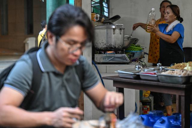 Women cook at a curbside canteen in Manila on April 7, 2026. While sticker shock at petrol stations has garnered the biggest headlines since the war in the Middle East forced the partial closure of the Strait of Hormuz, the rising price of LPG has hit the import-dependent archipelago's humble street food vendors hard. (Photo by Jam STA ROSA / AFP) / TO GO WITH AFP STORY: Iran-War-US-Israel-Philippines-economy-LPG, by Pam CASTRO